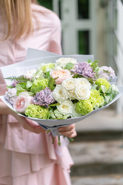 beautiful luxury bouquet of mixed flowers in woman hand. the work of the florist at a flower shop. A small family business. photo outside