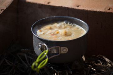 A closeup of a boiling pot on a gas primus cooking dinner for hikers. Outdoors kitchen.