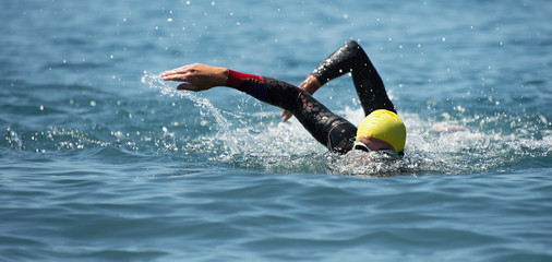 Triathlon long distance swimming, people in wetsuit swimming at triathlon
