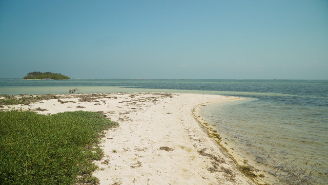 Tropical island with white sandy beach in blue lagoon. Tondol white sand beach with turquoise water. Seascape, ocean and beautiful beach. Philippines, Anda, Pangasinan. Travel concept.
