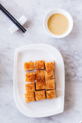Golden Crispy Pork Belly cut in cube served with mustard and chopsticks.