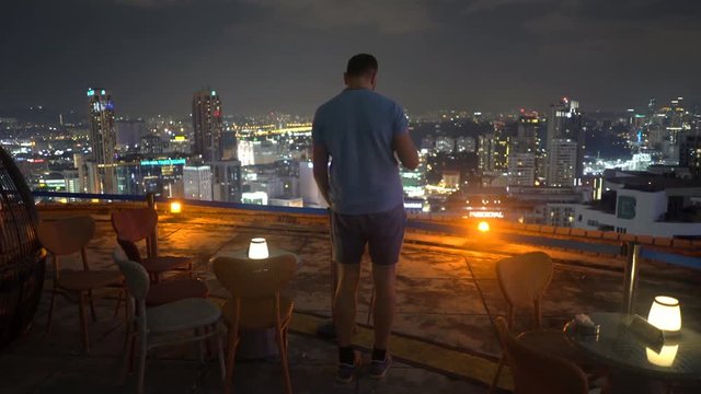 Drunk man drinking beer skybar at night
