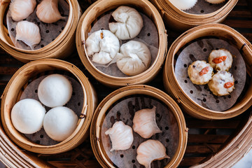 Closeup top view of Dim sum set: Barbecued pork bun, Shrimp dumpling, Sweet cream buns, Shrimp shumai topping with goji berry served in steamer baskets.