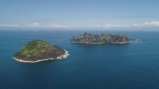 Small rocky islands in the sea, blue sky and clouds. Dos Hermanas, Palau, Santa Ana. Aerial view of seascape with tropical islands in the ocean.