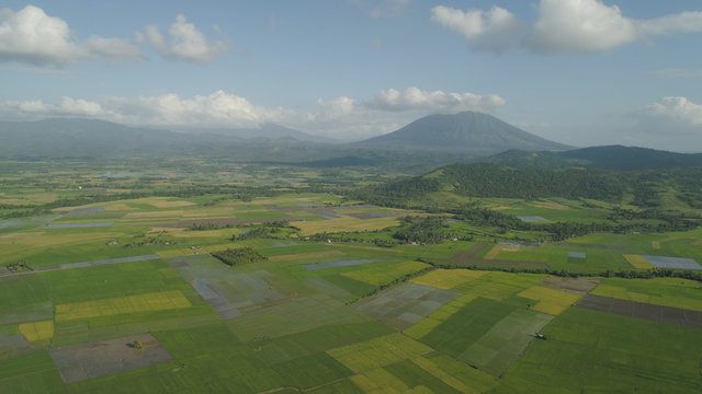 Mountain valley with farmland, rice terraces near mount Iriga. Aerial view mount with green tropical rainforest, trees, jungle with sky. Philippines, Luzon. Tropical landscape