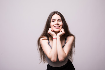 Pleased lovely brunette woman posing with arms near face while looking at the camera over grey background
