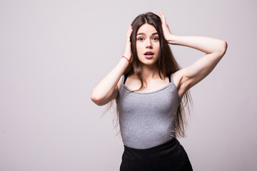 Surprised shocked young woman standing with opened mouth over grey background