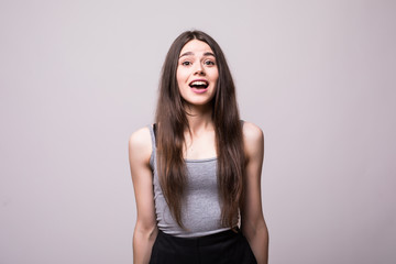 Fototapeta premium Shocked young woman looking at camera with mouth open isolated on grey