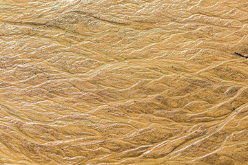 Beautiful sand patterns on the shore of baltic sea. Abstract, colorful background of sand on the beach. Shallow depth of field.