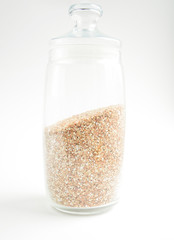 transparent glass container with buckwheat on a light background