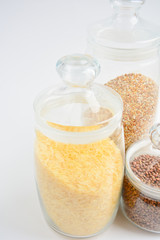 three transparent containers with a grain of rice, buckwheat and lentils on a light background