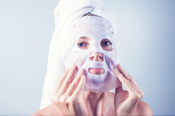Young girl with facial mask looking at camera over white background. Cosmetic procedure. Beauty spa and cosmetology.