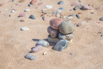 Fototapeta na wymiar Beautiful smooth sea stones in the sands of the beach. Closeup photo of stone textures and shapes.