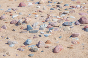 Beautiful smooth sea stones in the sands of the beach. Closeup photo of stone textures and shapes.