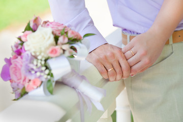Obraz na płótnie Canvas wedding bouquet and hands of newlyweds