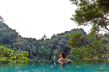 girl in the tropic jungle pool with a glass of champagne