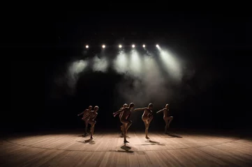 Fotobehang Een groep kleine balletdansers repeteert op het podium met licht en rook © nagaets