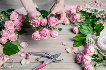 Florist at work. Elegant female hands collect a wedding bouquet of pink roses. People in the process of work