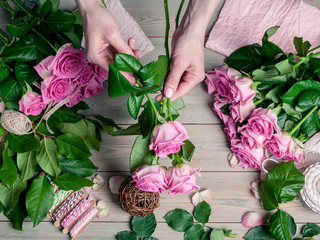 Fototapeta na wymiar Florist at work. Elegant female hands collect a wedding bouquet of pink roses. People in the process of work