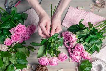 Florist at work. Elegant female hands collect a wedding bouquet of pink roses. People in the process of work