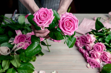 Graceful female hands collect a bouquet of pink roses. Florist at work