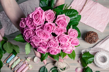 Graceful female hands collect a bouquet of pink roses. Florist at work