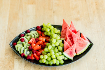 Fruit platter with watermelon, grapes, strawberries, kiwifruit and raspberries