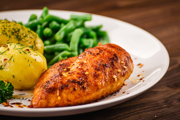 Grilled chicken fillet and vegetables on wooden table