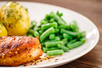 Grilled chicken fillet and vegetables on wooden table