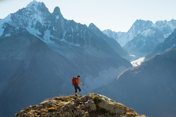 A hiker in the French Alps with the high mountain peaks and glaciers in the distance - 205625973