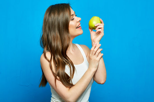 Young woman biting green apple.