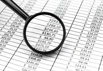 Magnifying glass over document with financial data. Business concept.