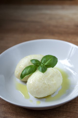 Potato dumplings with meat, olive and fresh basil on a white plate
