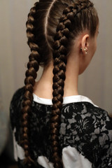two braids, a haircut close-up of her own hair, details of the hairstyle, hairdressing art on her head girl