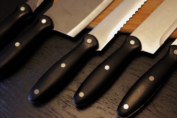 A set of professional kitchen knives on a black table..