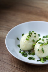 Potato dumplings with meat, olive and fresh green onion on a white plate