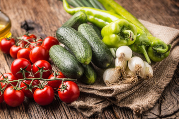Fresh vegetable onion cucumber pepper and tomatoes on rustic oak table