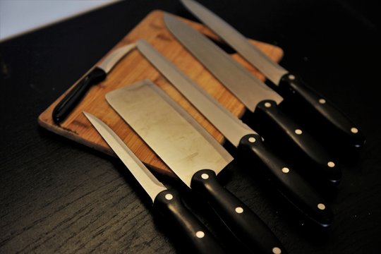 A set of professional kitchen knives on a black table..