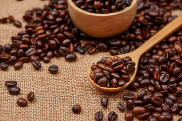 Wooden bowl with roasted coffee beans on rustic background.