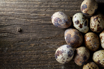 Spotted quail eggs arranged on the background of old wooden boards, with copy-space, selective focus.