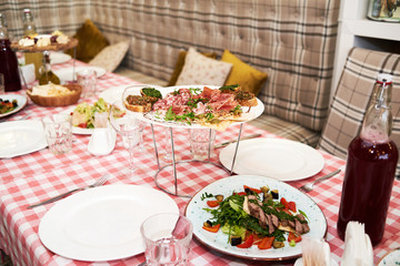 Meat antipasto platter on dinner table. Cold meat plate with prosciutto, salami, ham, bacon, sandwiches and olives on white plate, copy space. Italian prosciutto crudo or jamon with arugula. Raw ham