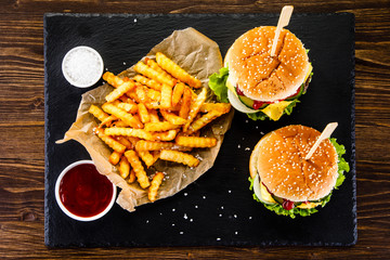 Tasty cheeseburgers with french fries served on fashionable black desk