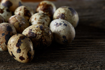 Spotted quail eggs arranged on the background of old wooden boards, with copy-space, selective focus.