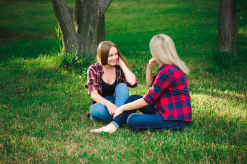 Fototapeta premium lifestyle and people concept: Two young girl friends sitting together and having fun.