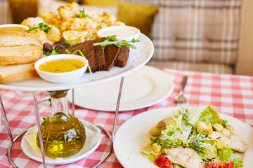 Tasty sliced bread with various dip sauces and herb on white plate and bottle of olive oil on dinner table, copy space. Toasted bread