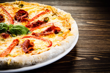 Pizza with ham and vegetables on wooden table