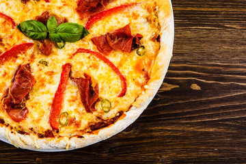 Pizza with ham and vegetables on wooden table