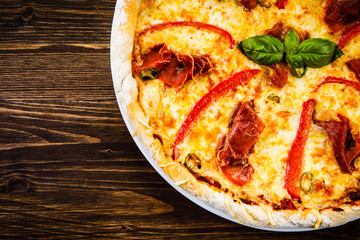 Pizza with ham and vegetables on wooden table