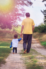 Young father and his little daughter walking in the park. Toned