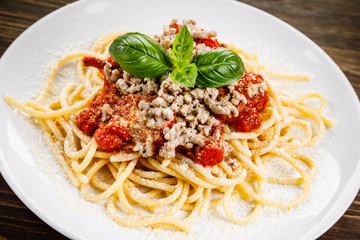 Pasta with meat and tomato sauce on wooden table